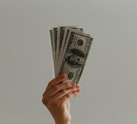 a person's hand holding up dollar bills in a fan